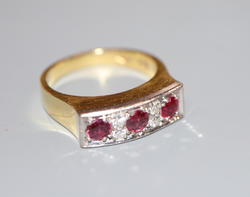 A modern 18ct yellow metal, three stone ruby and four stone diamond half hoop ring, size O, gross weight 7.4 grams.